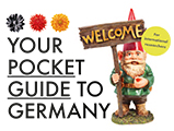 The cover of the brochure "Your pocket guide in Germany". It depicts a garden gnome with a welcome sign in his hands. On the left is written the brochure's title. 