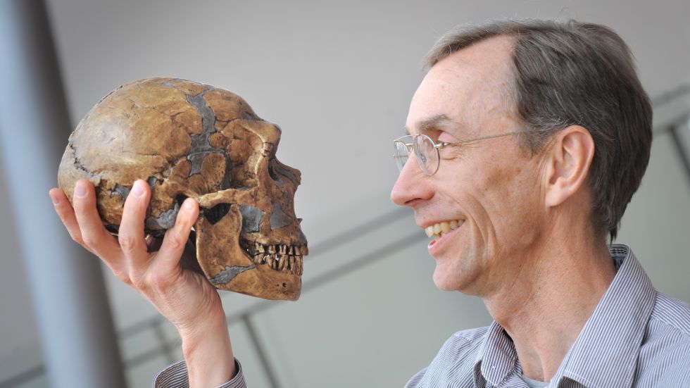 The Nobel Prize Winner 2022 Svante Pääbo holds a skull in his hand and looks into its eysockets.