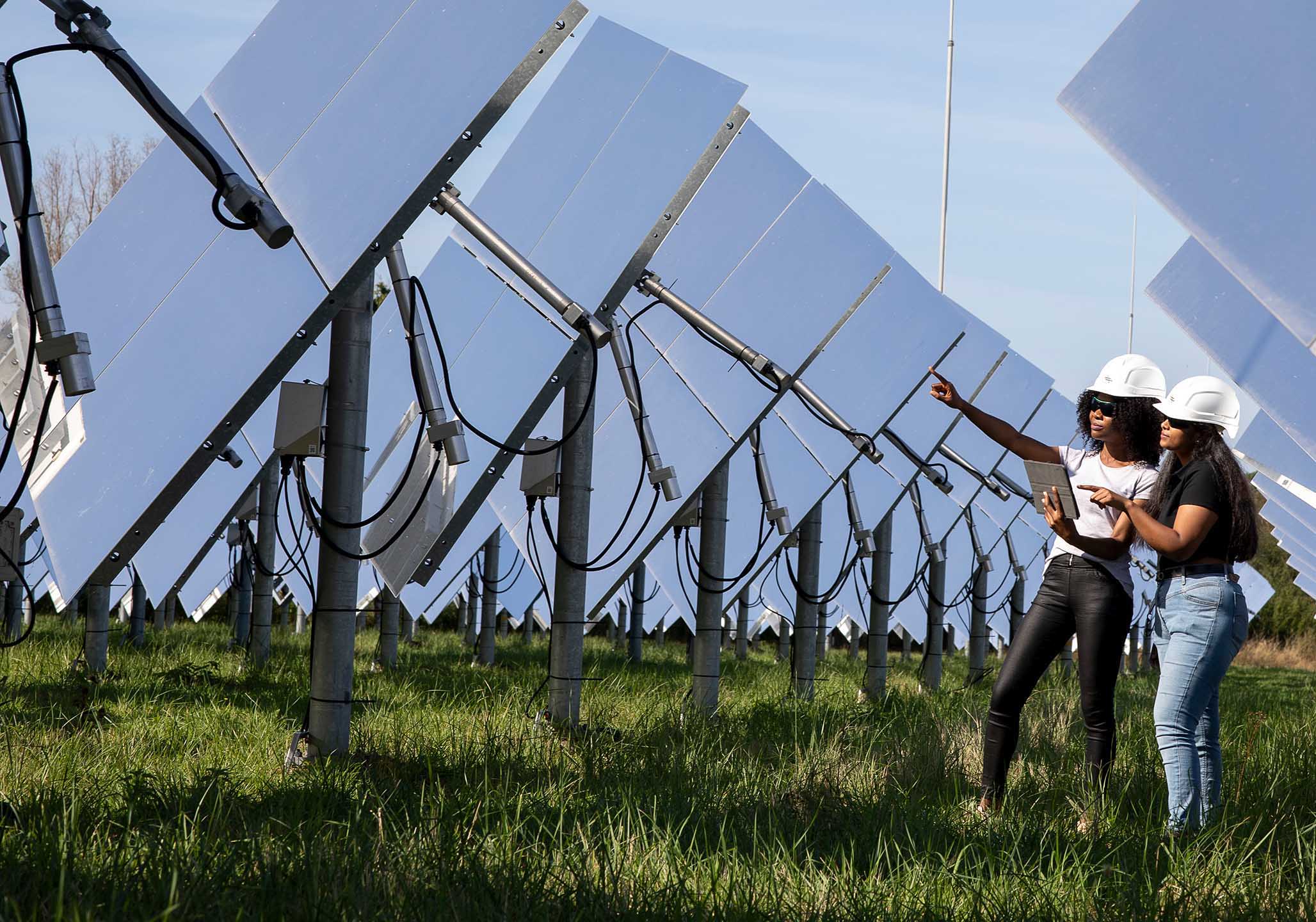 Two female researchers are standing in a large solar centre at the DLR Jülich. 