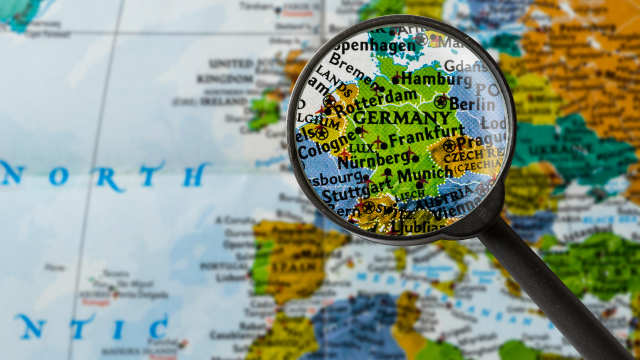 Eine Lupe vergrößert auf einer Weltkarte den Bereich von Deutschland.