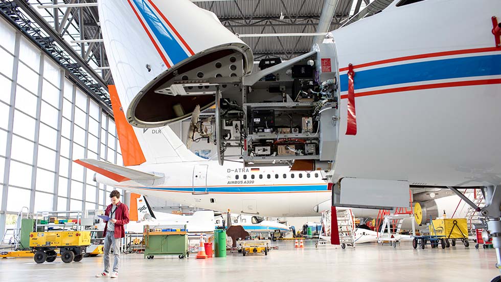 A scientist is standing next to an airbus, checking its mechanics. 